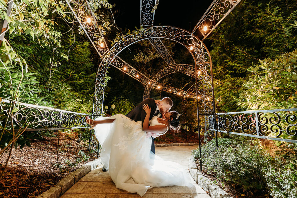 Groom dips his bride in fairytale wedding at Aria Banquet Hall in Connecticut for a night portrait.