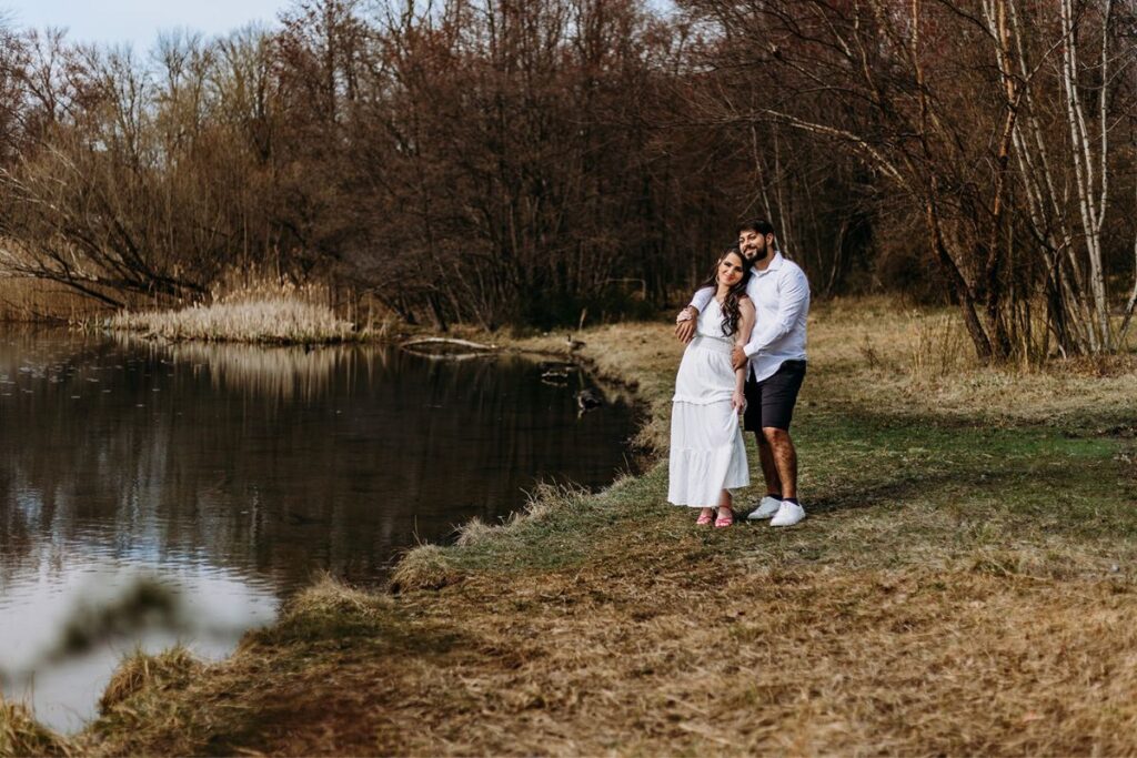 a couple posing by a lake for their engagement photoshoot 