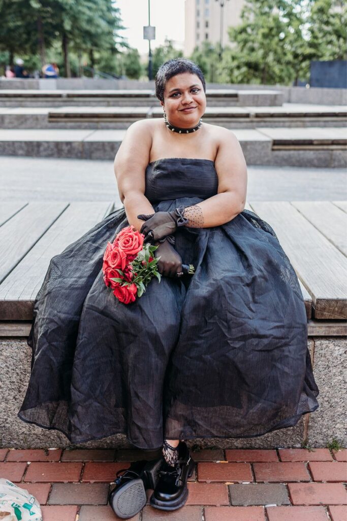 Tara wearing a black dress and holding red roses