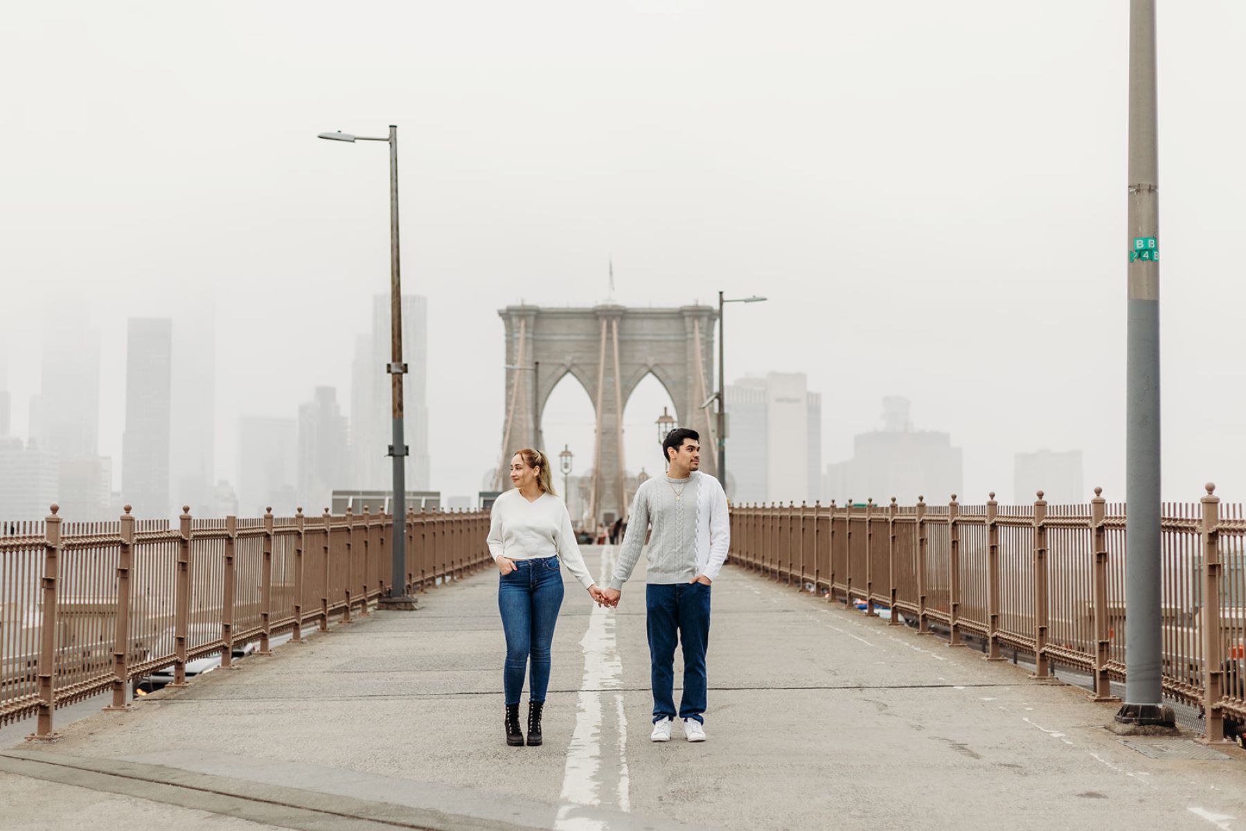 couple standing and holding hands on brooklyn bridge in new york