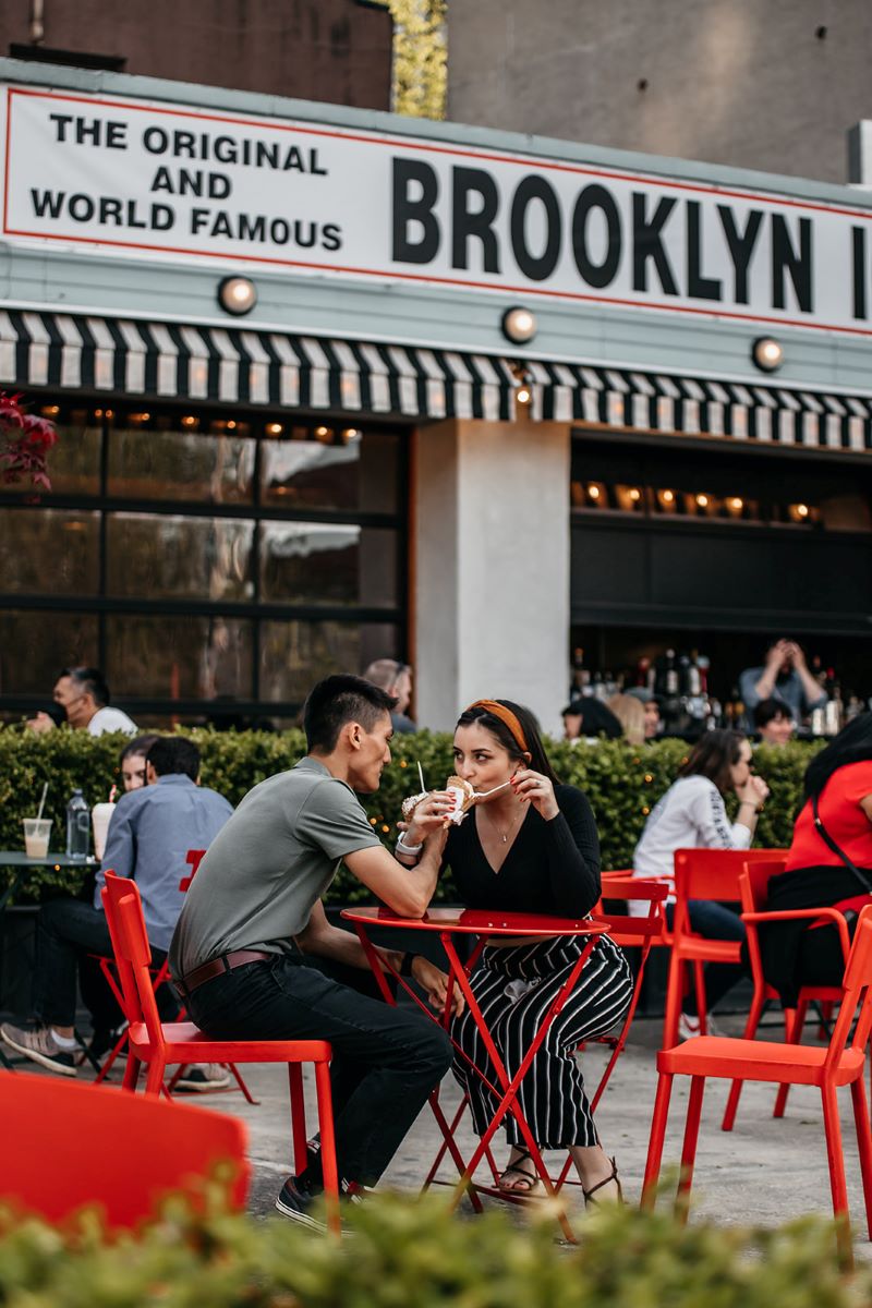 man and woman eating ice cream sitting in red chairs at a red table 