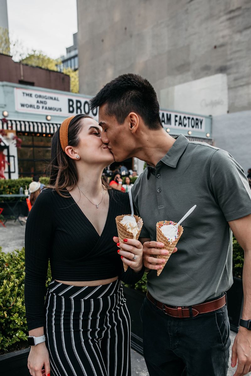 man giving woman a kiss while both are holding an ice cream cone 