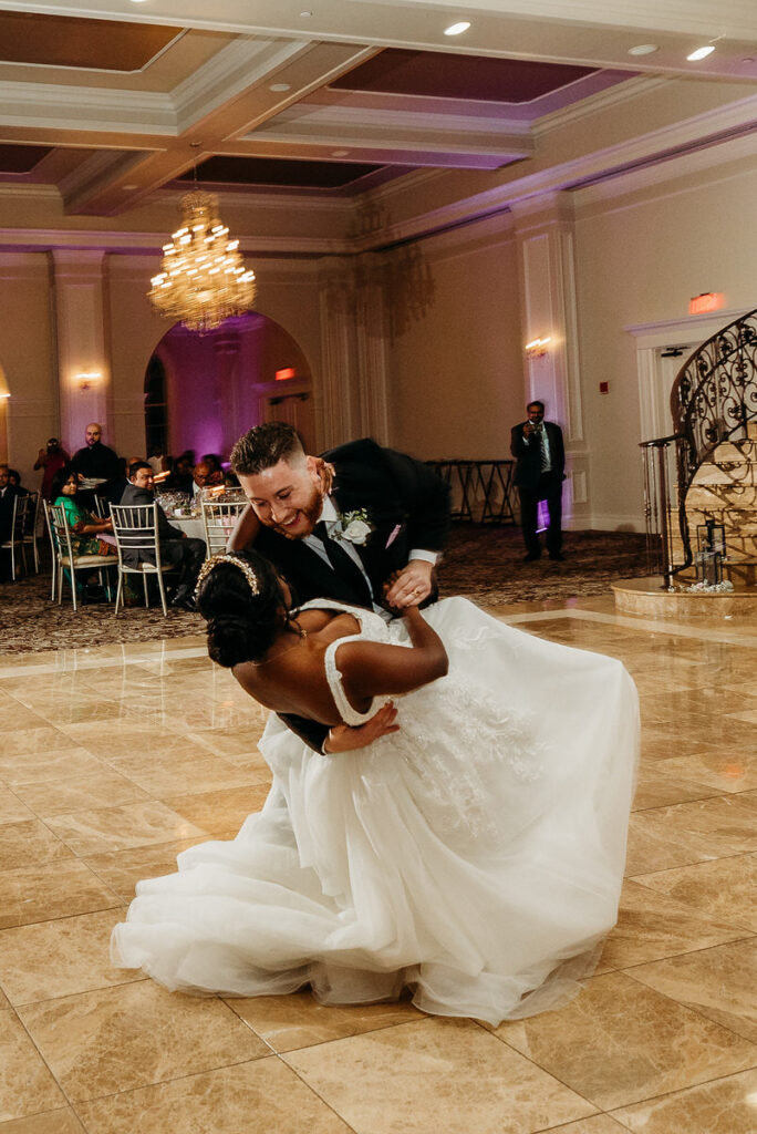 A groom dipping a bride during their first dance at their wedding reception 