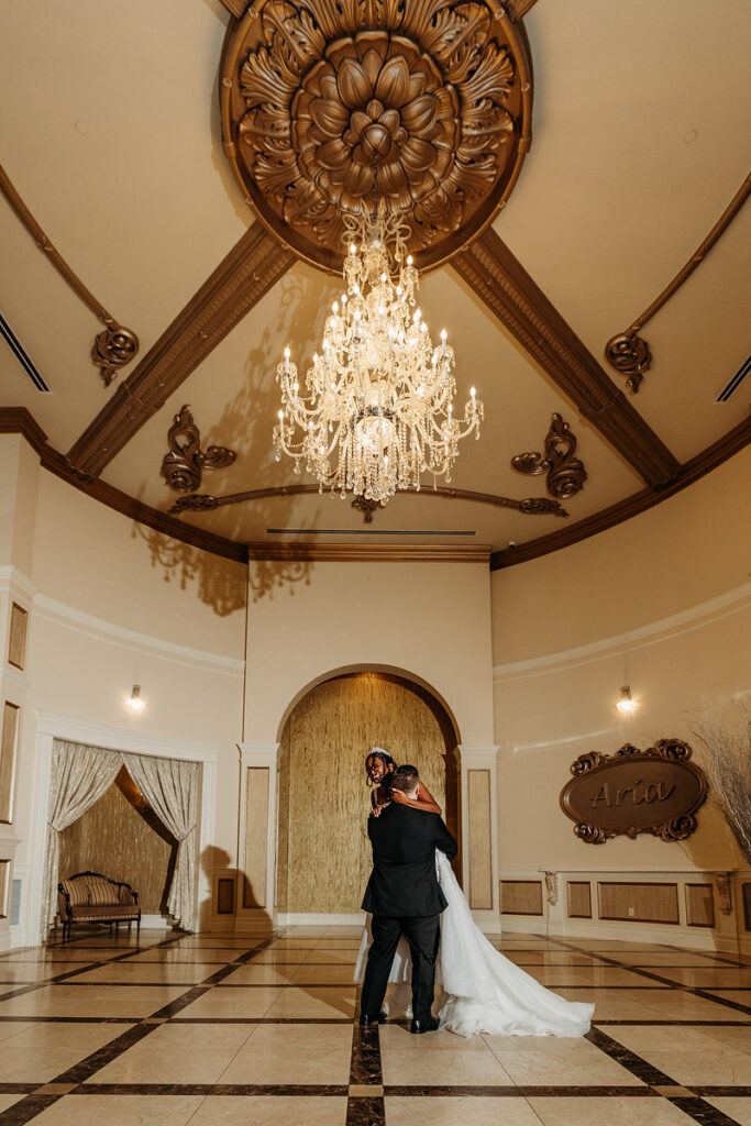 A groom lifting up a bride as she smiles 
