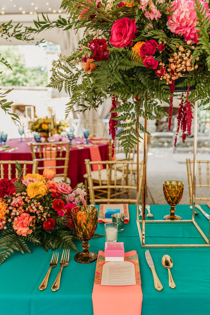 A wedding reception table with bright table clothes, flowers, and large arrangements. 