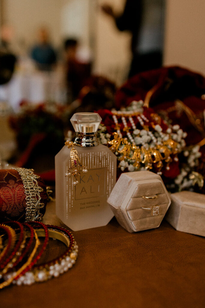 Various necklaces, bracelets, earrings, and rings sitting next to a bottle of perfume 