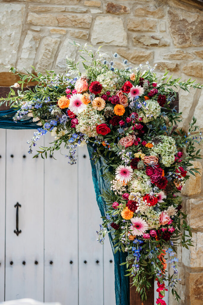 An extravagant floral arrangement on the corner of a wooden arch 