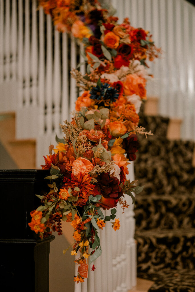 A bold and colorful floral arrangement down a staircase bannister 