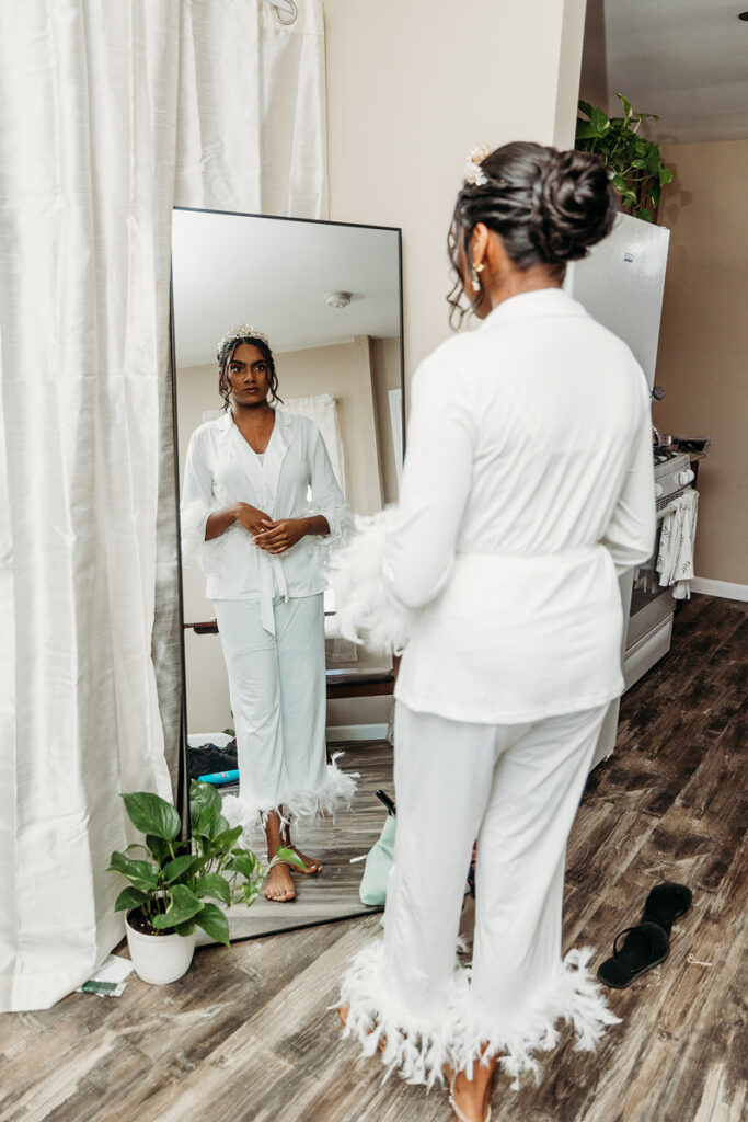 A bride in matching pajamas looking at herself in the mirror 