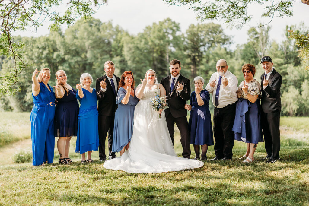 Newlyweds and their family smiling and holding up their ring fingers