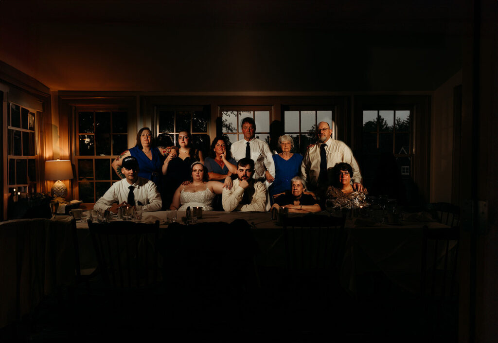 Newlyweds and their family sitting behind a table in a darkly lit room 
