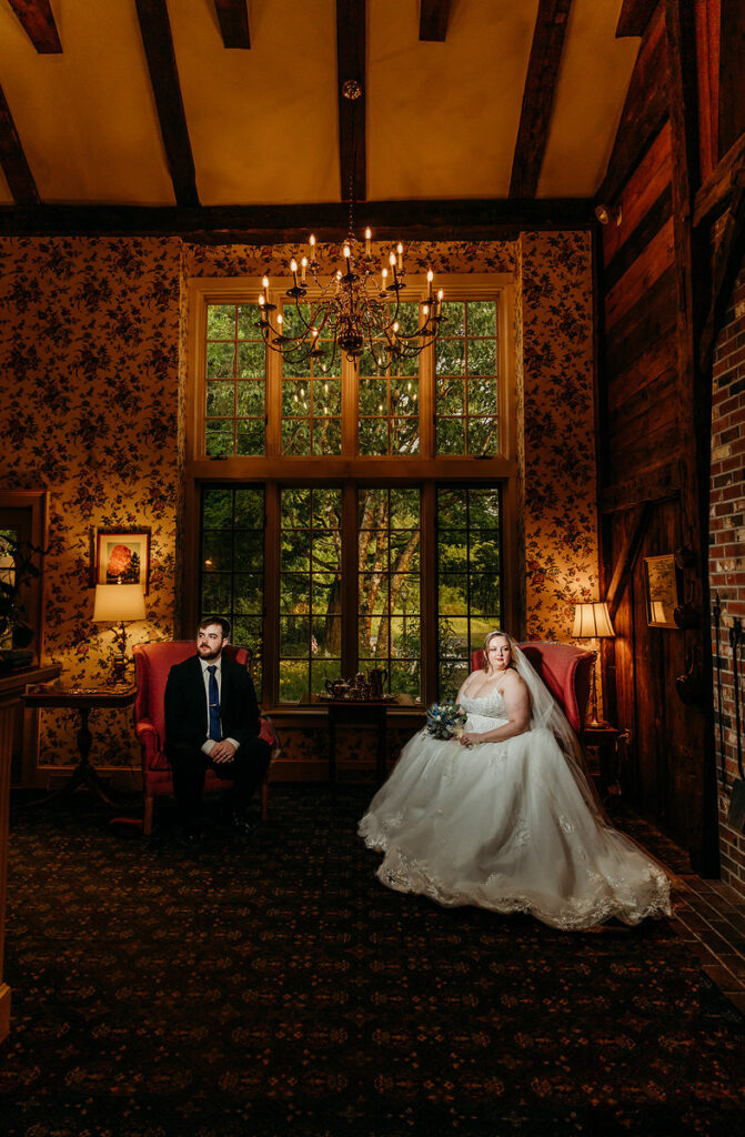 A newlywed couple sitting in separate chairs in an ornate room 
