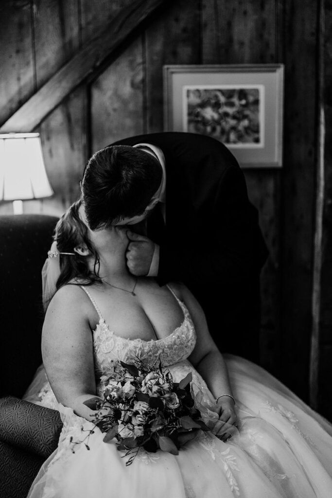 A person leaning down to kiss their partner who is sitting in a chair 
