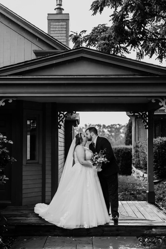 newlyweds kissing on the porch of an old home