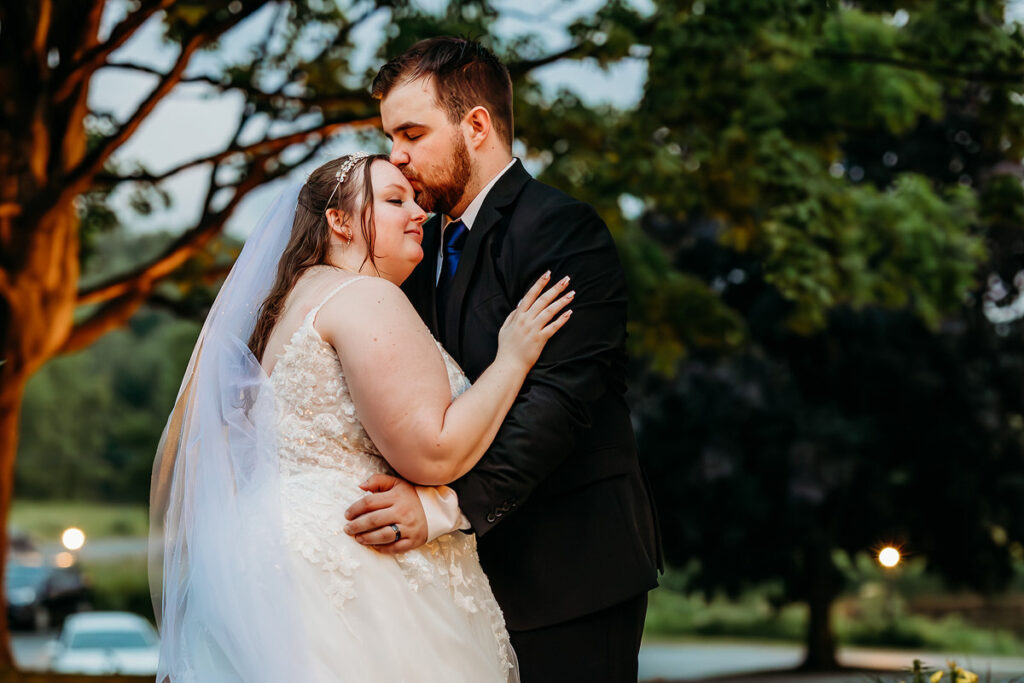 A person kissing their partner's head on their wedding day 