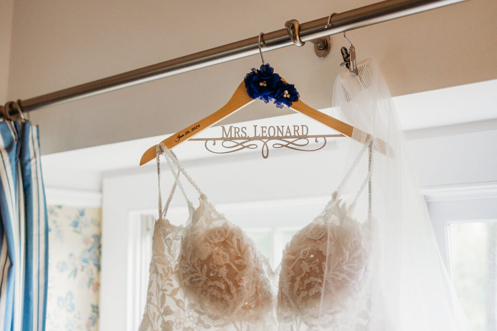 The top of a wedding dress on a hanger that has the words Mrs. Leonard 