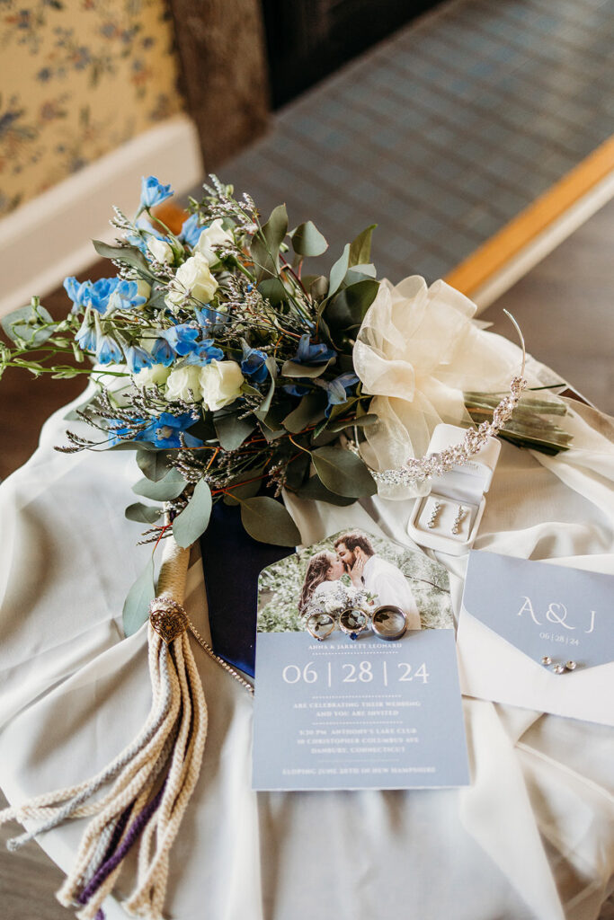 Wedding invitations, jewelry, and flowers laid out on a white veil 