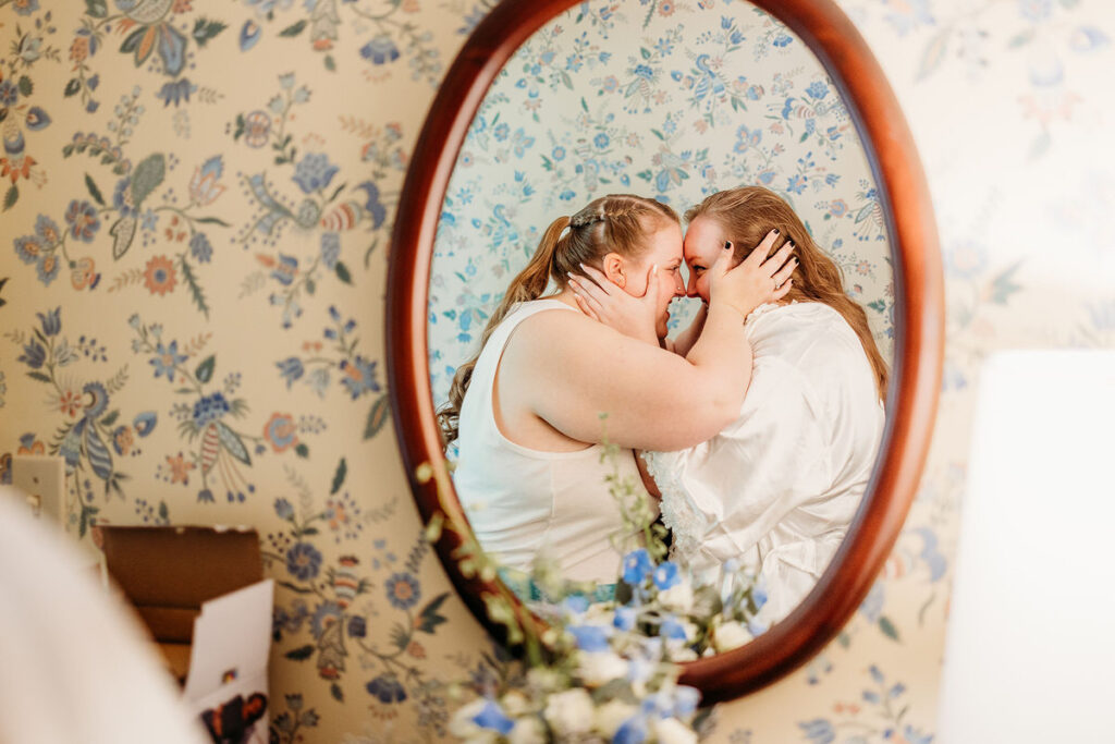 The reflection of two people holding their foreheads together 