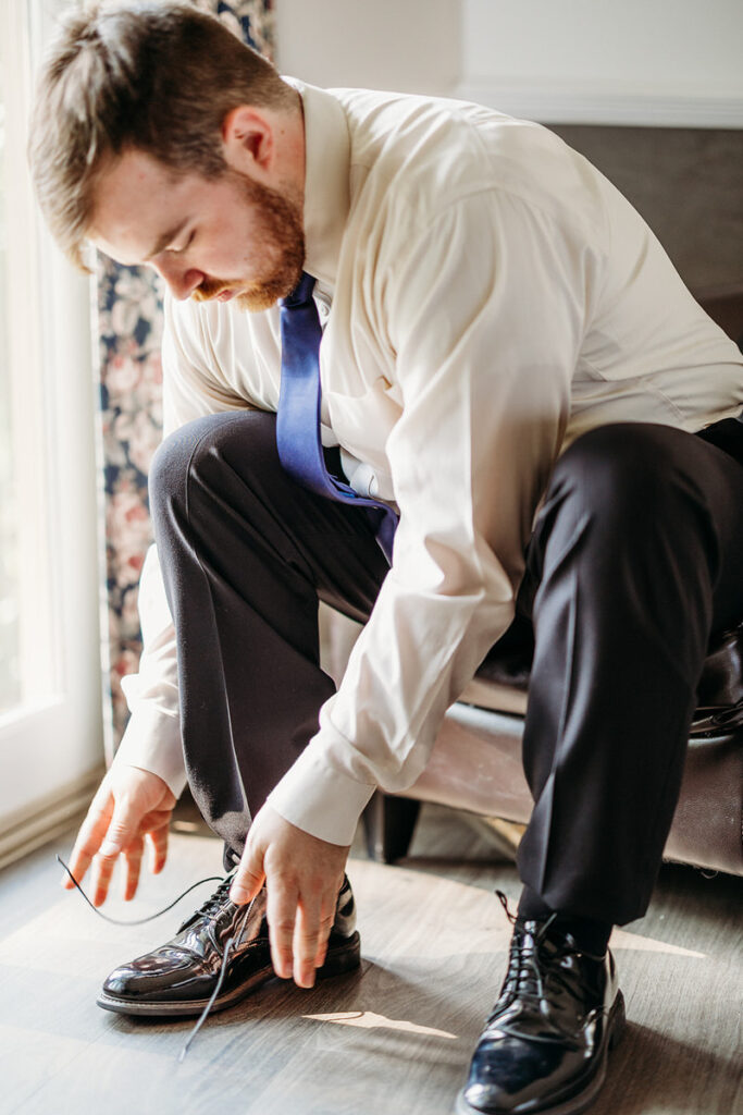 A person tying their shoes while sitting in a chair 
