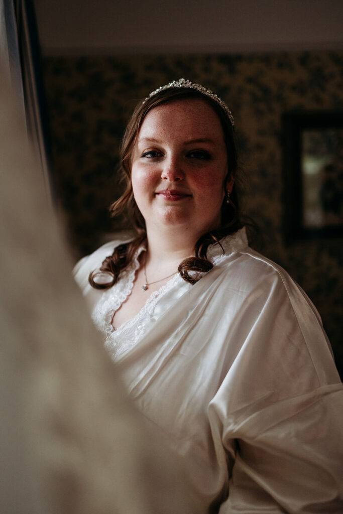 The reflection of a person in a wedding outfit smiling in a mirror 
