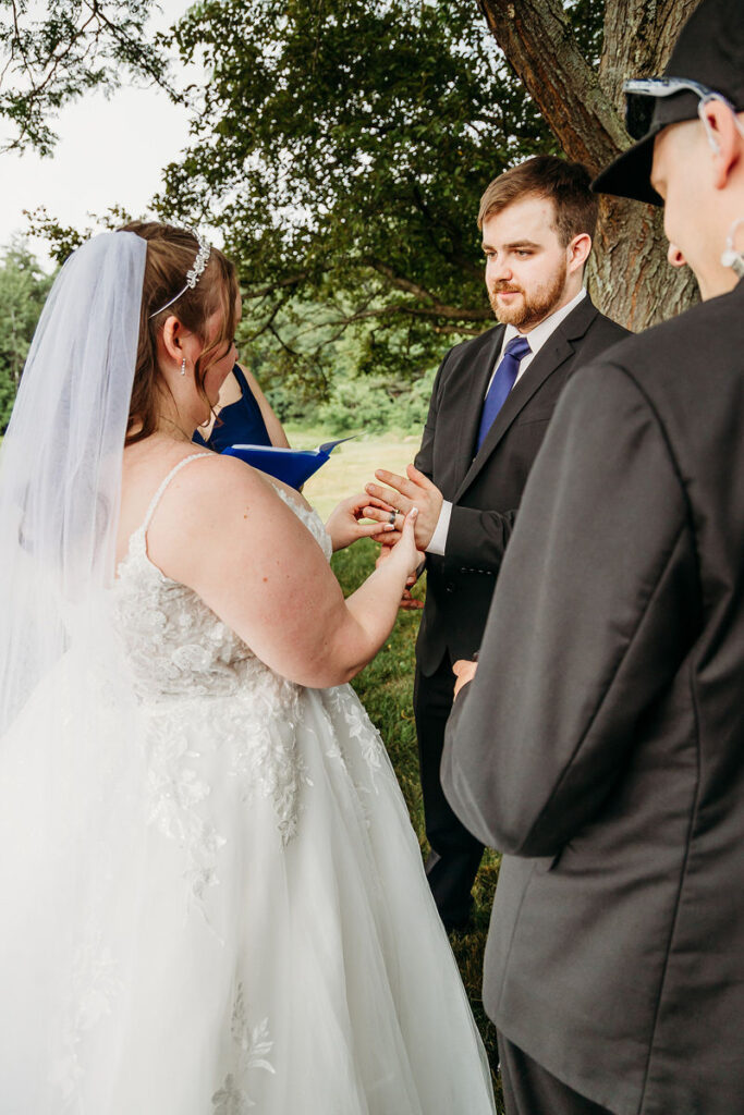 A person putting a ring on their partner's finger during their wedding ceremony 
