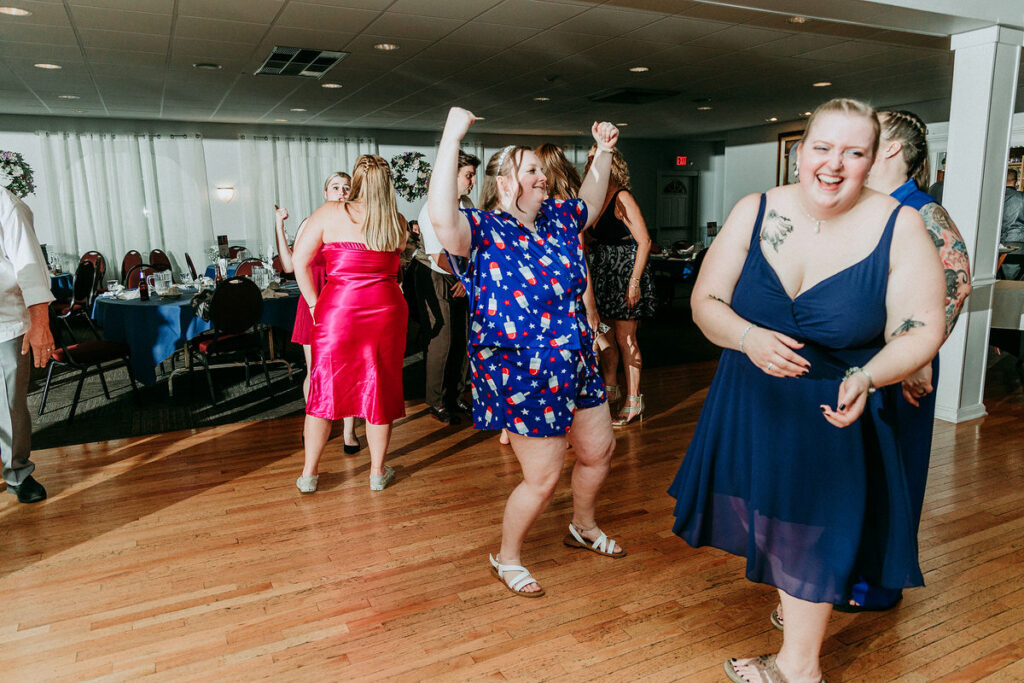 A bride in a casual post-wedding outfit dancing with guests 
