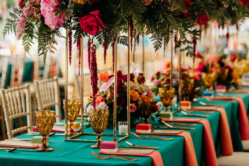 A wedding reception table with colorful napkins and large floral arrangements 