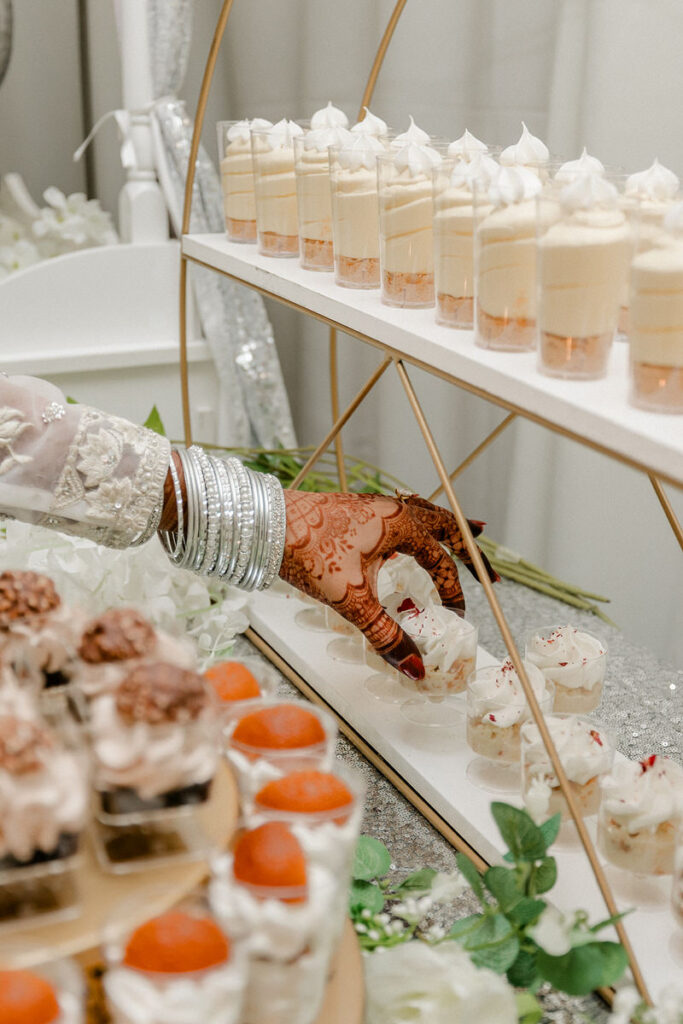 A hand reaching to pick up a mini cupcake from a tower of desserts 