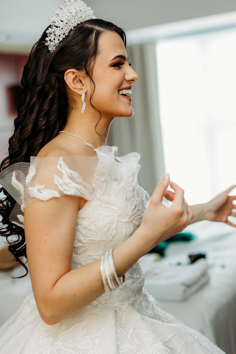 A woman in a white wedding dress wearing a tiara getting ready for her wedding 