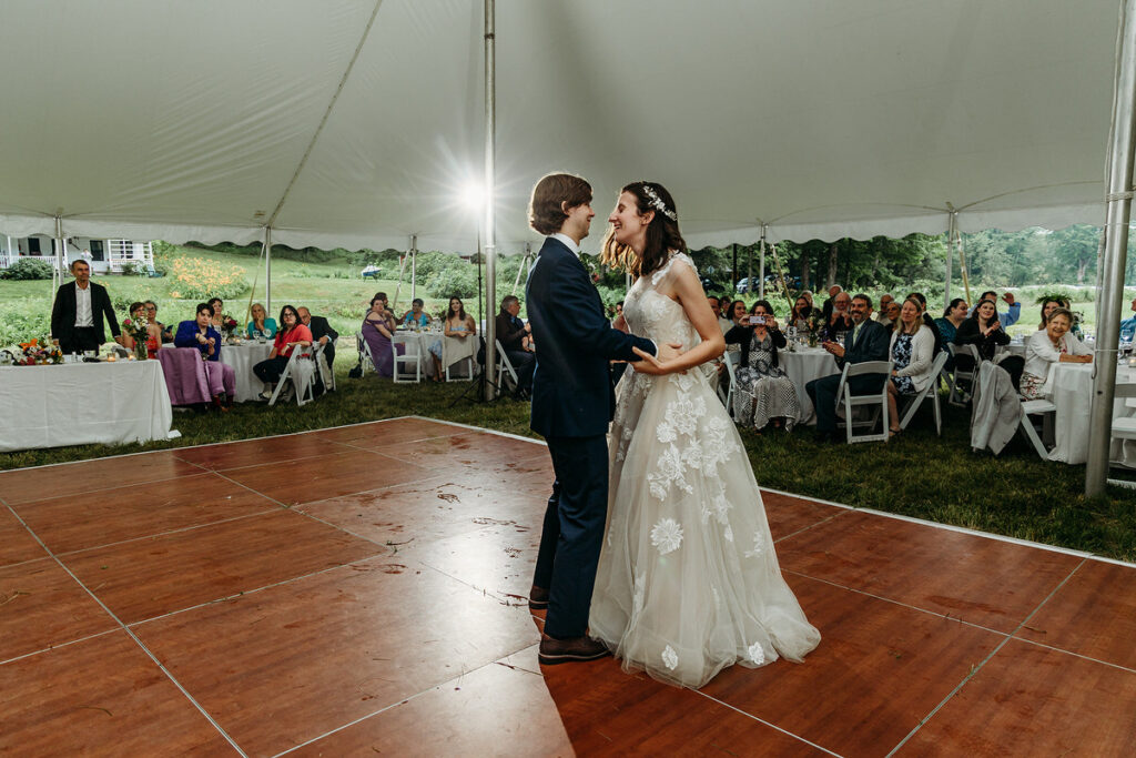 A newlywed couple during their first dance with guests watching on 