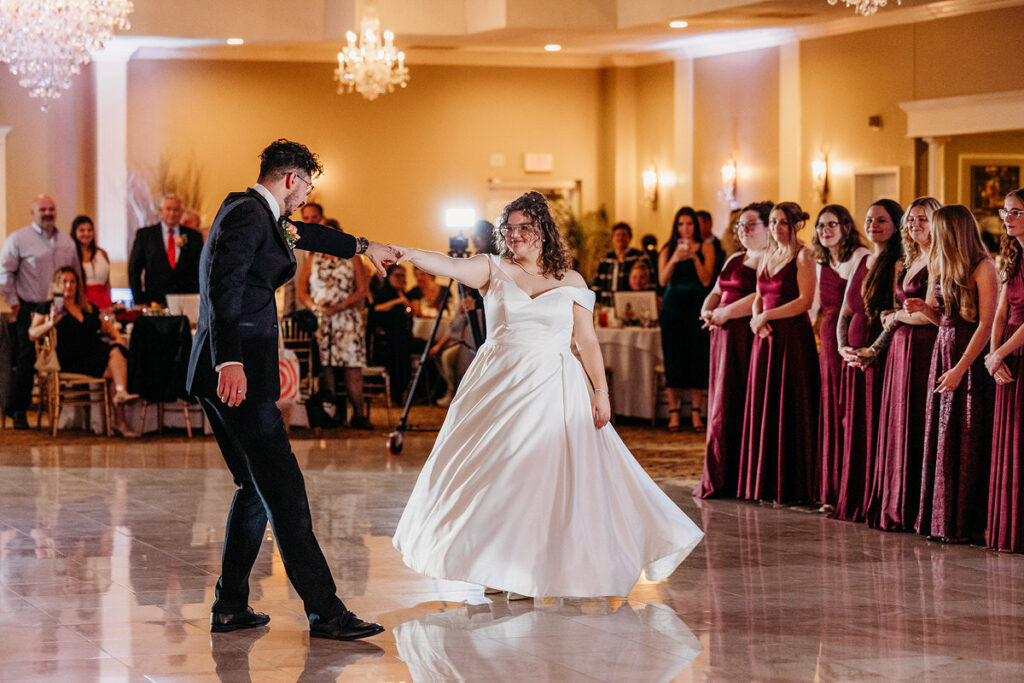 A newlywed couple smiling and dancing during their first dance at their reception 