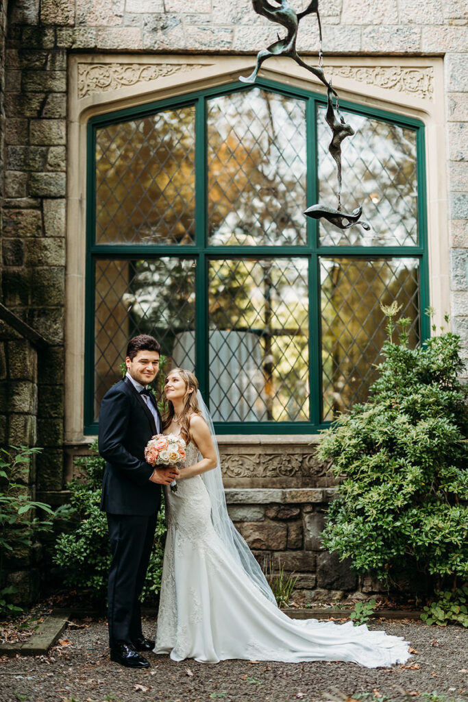 A newlywed couple standing together as one smiles at the other 