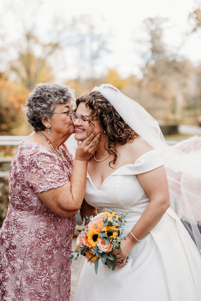 An older woman kissing the cheek of a bride 