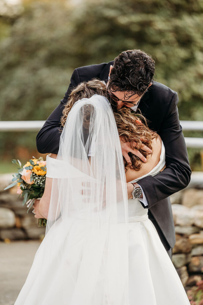 A newlywed couple hugging and leaning into each other 