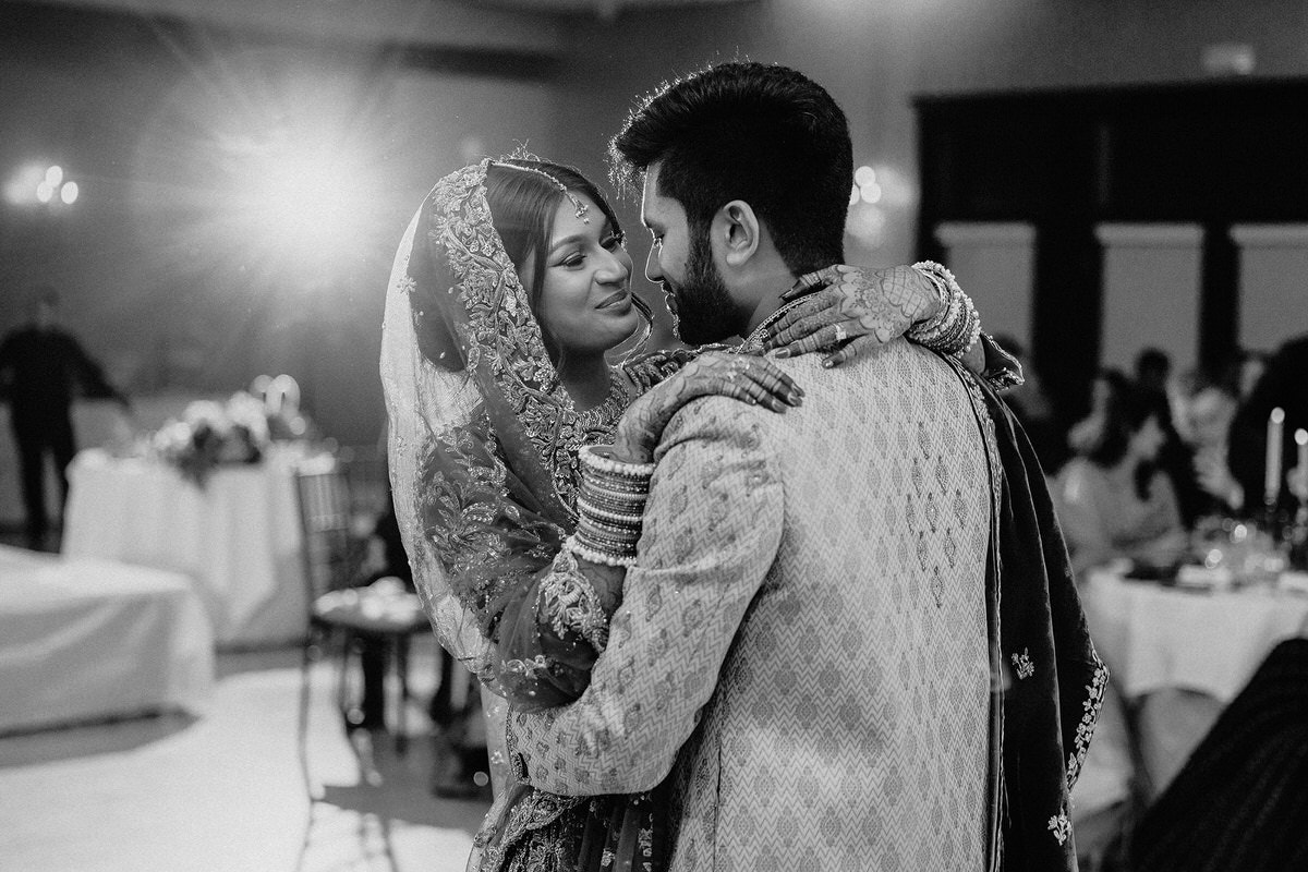 Fine art wedding photography of a couple standing close and dancing together at their wedding reception