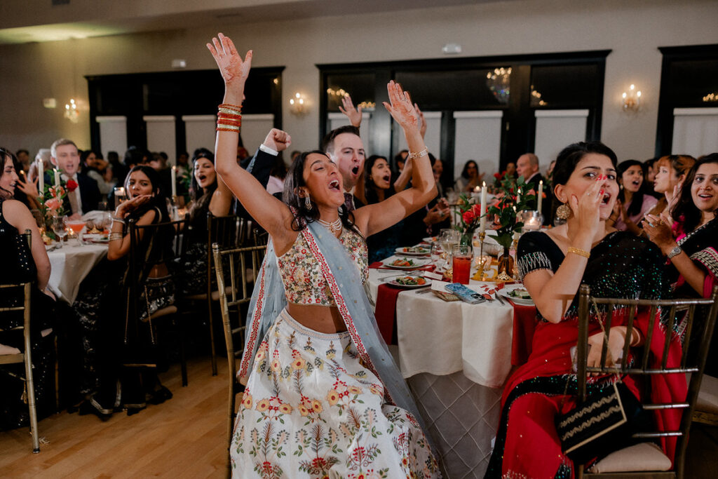 Wedding guests laughing and cheering while sitting at tables 