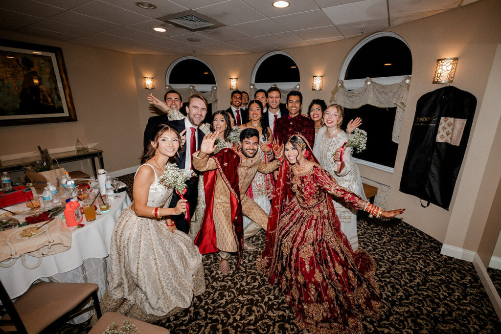 A newlywed couple and a group of guests smiling and celebrating together 