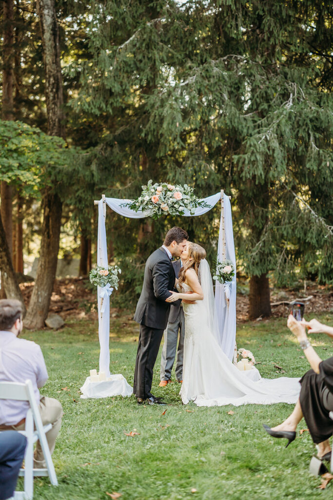 A wedding couple during their first kiss at their outdoor wedding 