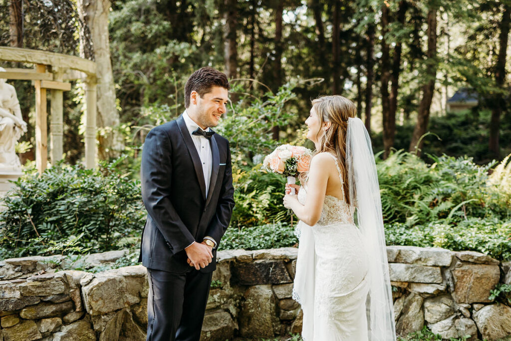 A wedding couple smiling at each other as one turns to face the other during their first look 