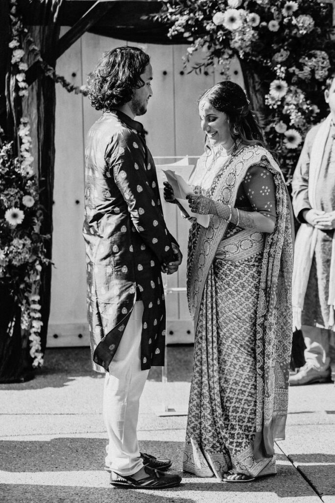 A wedding couple standing up together as one says their vows 
